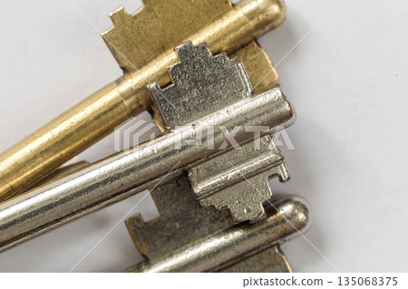 Close-up detail of old metallic keys stainless and yellow isolated on white background. Safety and security concept. 135068375