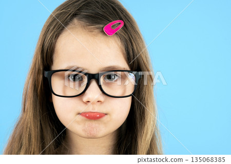 Close up portrait of a child school girl wearing looking glasses isolated on blue background. 135068385
