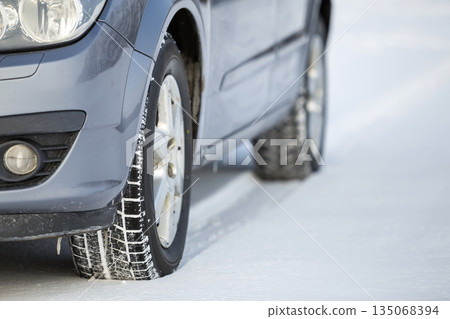 Close up of a car tire parked on snowy road on winter day. Transportation and safety concept. 135068394