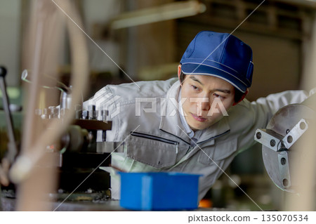 Male worker operating a machine in a factory 135070534