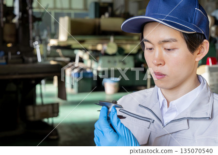 一名男工人正在用遊標卡尺檢查零件的尺寸。 135070540