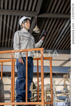 Young male worker working in a factory 135070570