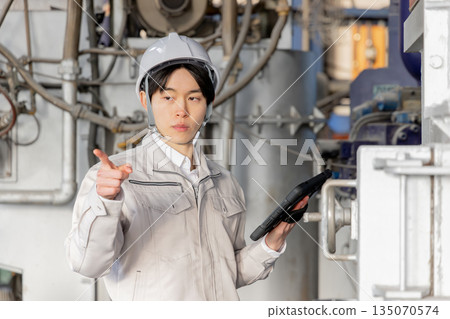 Young male worker working in a factory 135070574