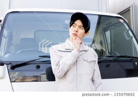 一名送貨員憂心忡忡地站在一輛卡車前 135070602