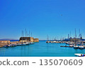 A view of the harbor of Heraklion, Crete, Greece, with ships in the foreground and the cityscape in the background 135070609