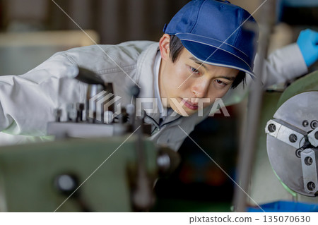 一名男工人在工廠操作機器 一名男工人在工廠操作機器 135070630