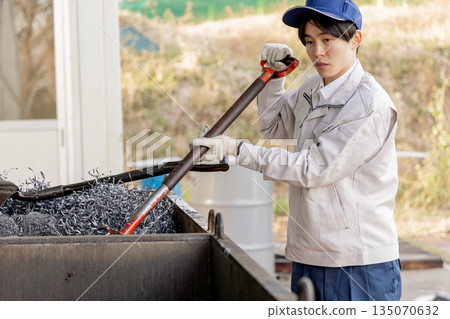 Male worker clearing away metal scrap 135070632
