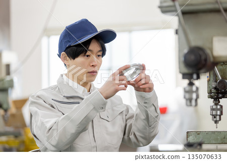 A male worker checking lathe-finished and milled products at a factory A male worker checking lathe-finished and milled products at a factory 135070633