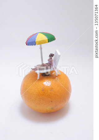 Whimsical Orange Beach Scene With Miniature Figure Relaxing Whimsical Orange Beach Scene With Miniature Figure Relaxing 135071364
