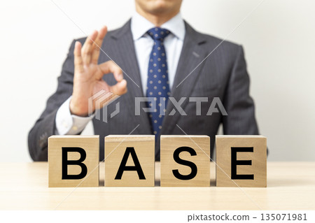 A businessman making an OK pose with a block that says "BASE" A businessman making an OK pose with a block that says "BASE" 135071981
