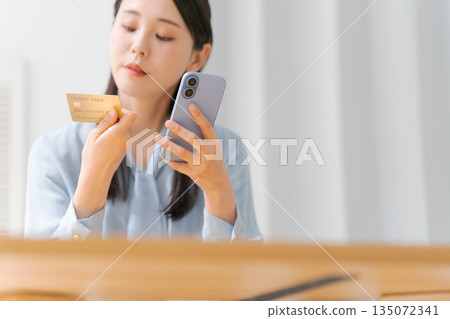 A woman with a smartphone and a credit card 135072341