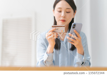 A woman with a smartphone and a credit card 135072344