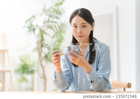 A woman with a smartphone and a credit card A woman with a smartphone and a credit card 135072348