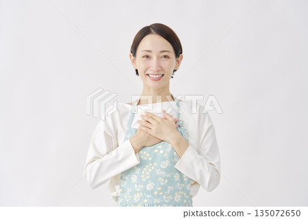身穿圍裙的女子，神情如釋重負，白色背景 135072650
