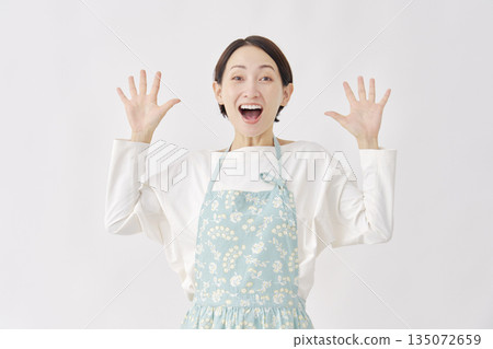 一位身穿圍裙、微笑著的女性，背景為白色。 135072659