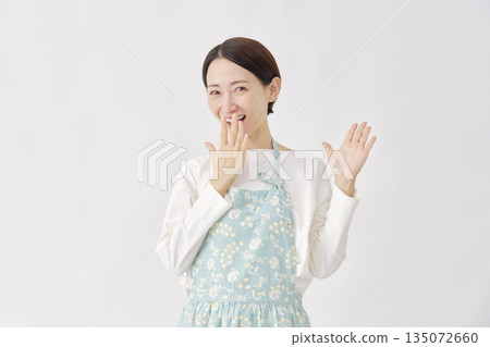 一位身穿圍裙、微笑著的女性，背景為白色。 135072660