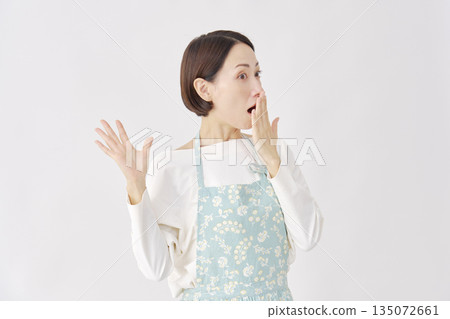 一位身穿圍裙、面露驚訝的女士，白色背景，面向右側。 135072661