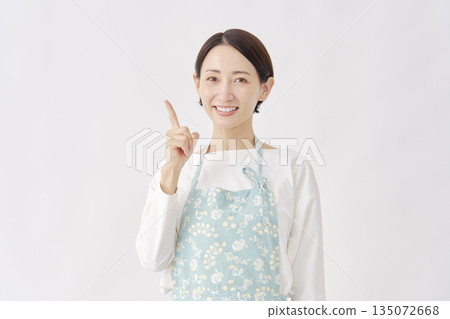 一位身穿圍裙的女子指向左側，白色背景 135072668