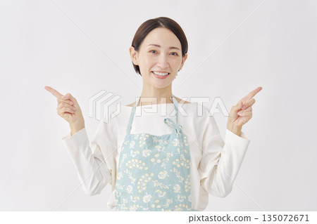 Woman wearing an apron pointing left and right, white background Woman wearing an apron pointing left and right, white background 135072671