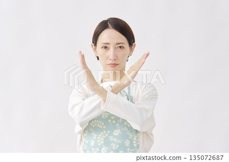 一位身穿圍裙的女子在白色背景上做出十字手勢。 135072687