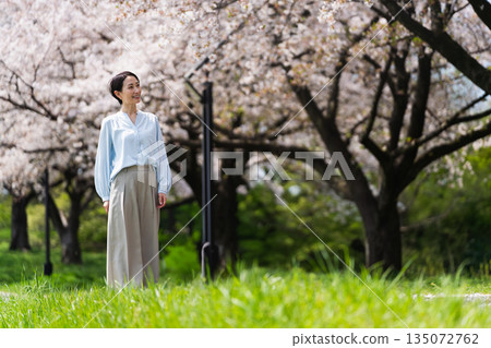 一位年輕女子沿著一排櫻花樹漫步。生活方式圖片 135072762