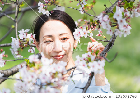 Young woman looking at cherry blossom petals Lifestyle image Young woman looking at cherry blossom petals Lifestyle image 135072766