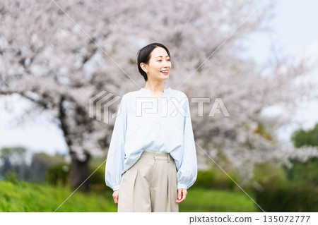 Young woman posing in front of a cherry blossom tree Lifestyle image Young woman posing in front of a cherry blossom tree Lifestyle image 135072777