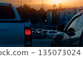 Rear side of pickup car with turn on brake light in dark tone. Environment traffic jams on the junction with many cars. Background of city and forest under light of evening sky. 135073024