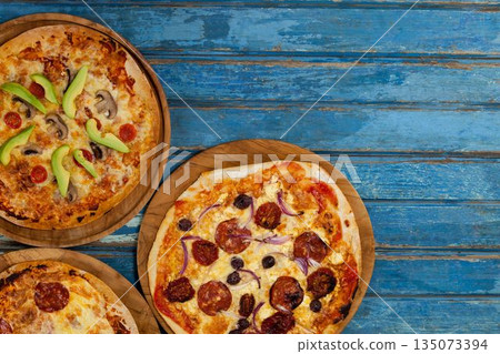 Fresh pizzas on blue wooden table Fresh pizzas on blue wooden table 135073394