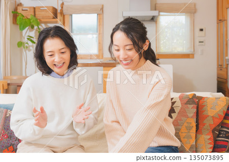 Mother and daughter discussing a trip in the living room 135073895