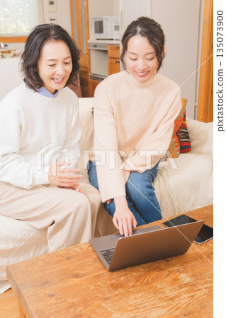 Mother and daughter discussing a trip in the living room Mother and daughter discussing a trip in the living room 135073900