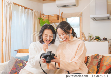 一對母女在客廳裡一邊看著照片,一邊愉快地談論著她們的旅行回憶。 一對母女在客廳裡一邊看著照片,一邊愉快地談論著她們的旅行回憶。 135073901