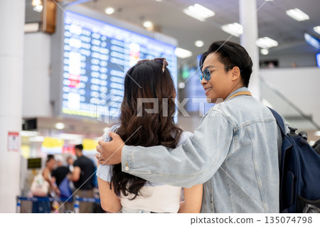 Asian tourist couple a man hugging woman while going on a trip and waiting for departure in airport. Asian tourist couple a man hugging woman while going on a trip and waiting for departure in airport. 135074798