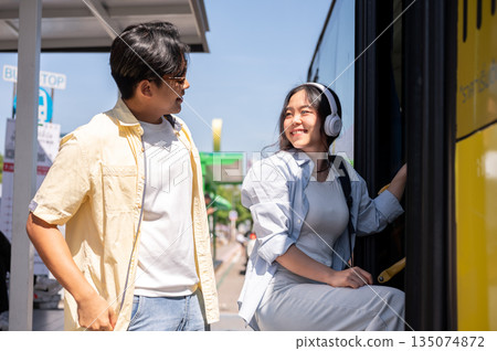 Asian tourist couple man and woman looking at each other before going in or getting on shuttle bus. 135074872