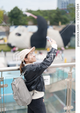 Happy woman traveler travel in Dujiangyan city. Tourist sightseeing Yangtianwo Square and Guanxian Ancient City near Chengdu. Landmark and popular for tourism attraction in Sichuan, China Happy woman traveler travel in Dujiangyan city. Tourist sightseeing Yangtianwo Square and Guanxian Ancient City near Chengdu. Landmark and popular for tourism attraction in Sichuan, China 135075864