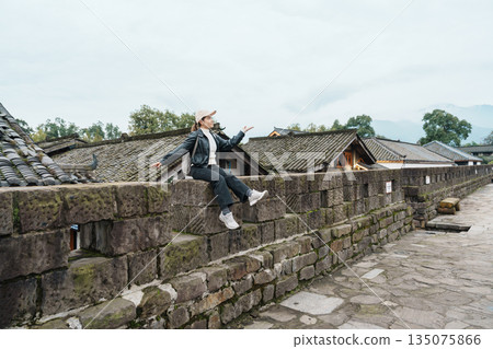 Happy woman traveler travel in Dujiangyan city. Tourist sightseeing the Ming City Wall at Guanxian Ancient City near Chengdu. Landmark and popular for tourism attraction in Sichuan, China Happy woman traveler travel in Dujiangyan city. Tourist sightseeing the Ming City Wall at Guanxian Ancient City near Chengdu. Landmark and popular for tourism attraction in Sichuan, China 135075866