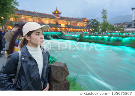 Happy woman traveler travel in Chengdu city. Tourist sightseeing Dujiangyan irrigation system consists of Nanqiao and Langqiao Bridge near ancient city of Guanxian, Sichuan, China Happy woman traveler travel in Chengdu city. Tourist sightseeing Dujiangyan irrigation system consists of Nanqiao and Langqiao Bridge near ancient city of Guanxian, Sichuan, China 135075867