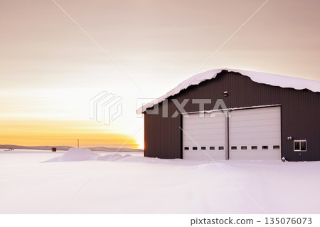 Warehouse in snow, industrial building in sunset light in winter. Warehouse in snow, industrial building in sunset light in winter. 135076073