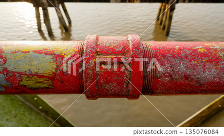 Close Up of Weathered Red Metal Railing Pipe with River Background Close Up of Weathered Red Metal Railing Pipe with River Background 135076084