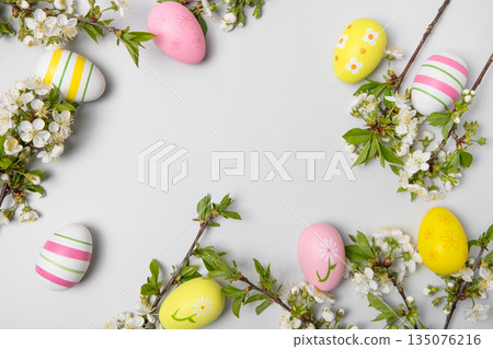 Easter colored painted eggs and blooming spring cherry branches on gray background in shape of frame with space for text and greetings. Easter and spring concept. Spring background 135076216