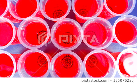 Red Syrup Drinks in Clear Plastic Cups Top View, Refreshing Sweet Beverage Background for Party and Celebration 135076253