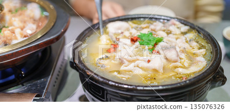 Woman tourist eating Sichuan Fish with Pickled Mustard Greens or Suan Cai Yu in restaurant. Popular foods for tourist eating in Chengdu, Chongqing and China. Chinese Asia and Sichuan foods concept 135076326