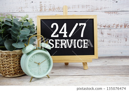 24 Hr. 7 Day Service text written on blackboard with alarm clock on wooden background 24 Hr. 7 Day Service text written on blackboard with alarm clock on wooden background 135076474