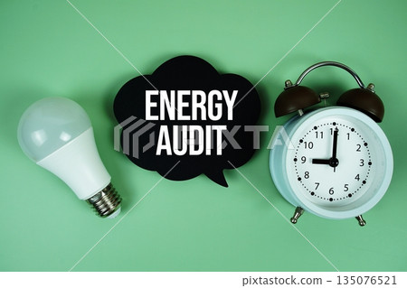 Energy Audit text with light bulb and alarm clock on green background 135076521