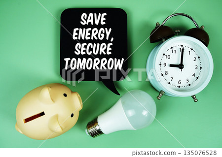 Save Energy, Secure Tomorrow with light bulb, piggy bank and alarm clock on green background 135076528