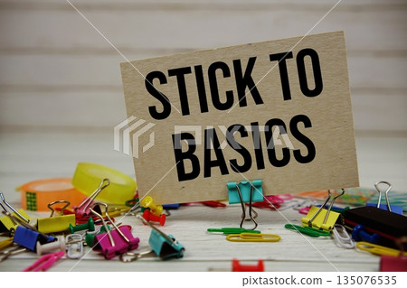 Stick To Basics text on paper card with stationary on wooden background Stick To Basics text on paper card with stationary on wooden background 135076535