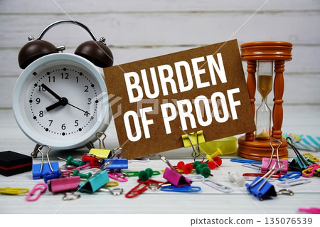 Burden Of Proof text on paper card with alarm clock and stationary on wooden background 135076539