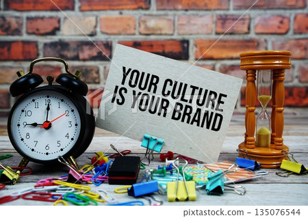 Your Culture Is Your Brand text on paper card with alarm clock and stationary on wooden background 135076544