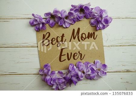 Best Mom Ever text written on paper card with flower decoration on wooden background 135076833