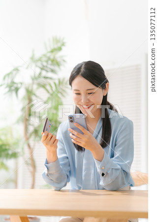 A woman with a smartphone and a credit card A woman with a smartphone and a credit card 135077112